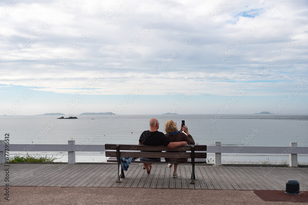 Un couple qui est assis sur un banc face à la mer en Bretagne Un couple qui est assis sur un banc face à la mer en Bretagne
