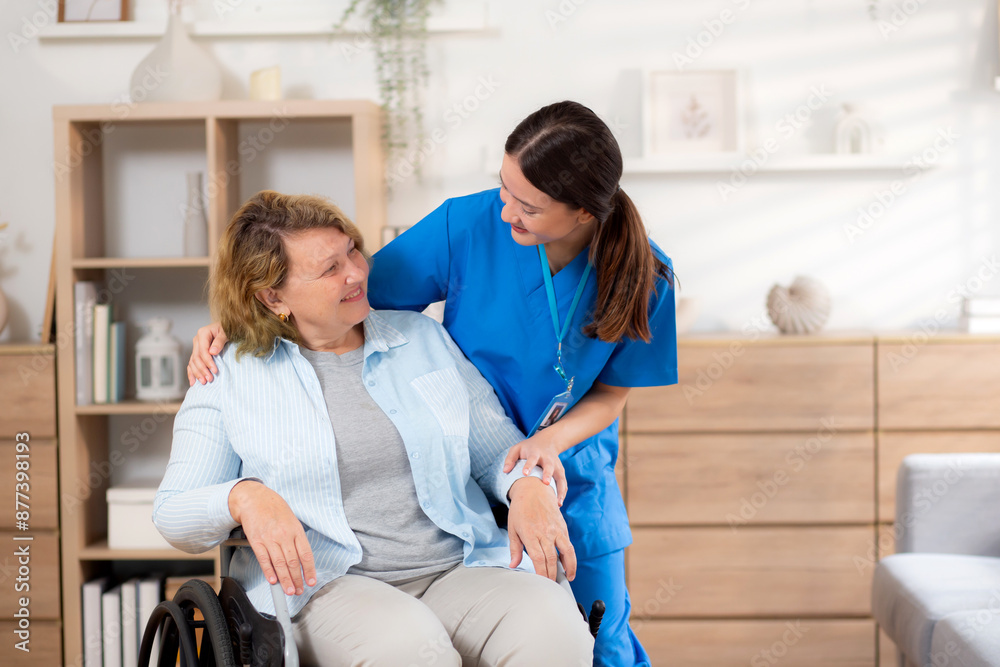 Caregiver asian woman care elderly sitting on wheelchair, consoling for encourage in living room at home, senior therapy and rehabilitation with doctor for rehab and treatment, insurance and medical. Caregiver asian woman care elderly sitting on wheelchair, consoling for encourage in living room at home, senior therapy and rehabilitation with doctor for rehab and treatment, insurance and medical.