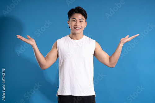 Portrait of asian guy wearing summer outfit and posing on blue background