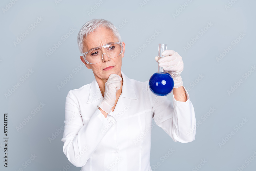 Photo of serious thoughtful old woman scientist look check liquid isolated grey color background Photo of serious thoughtful old woman scientist look check liquid isolated grey color background