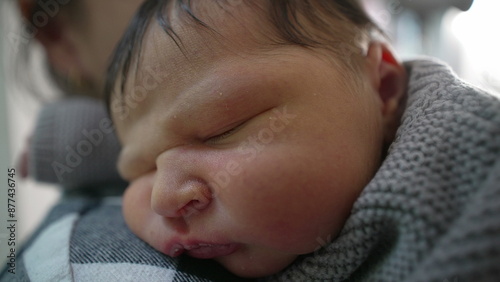 Macro close-up of Newborn baby sleeping peacefully on the mother’s shoulder, wrapped in a cozy knitted sweater. intimate and tender bond between mother and child