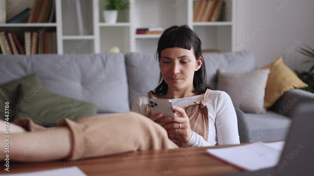 Positive young caucasian woman student or freelancer relaxing at home typing browsing products in internet online store reading news or social media profile on smartphone while take a break indoors Positive young caucasian woman student or freelancer relaxing at home typing browsing products in internet online store reading news or social media profile on smartphone while take a break indoors