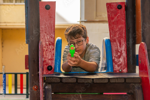 Summer Fun: Boy Playing with Water Gun in the Park. photo