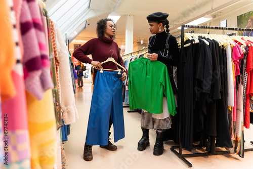 Lady customer shopping in modern clothing store, retail sales associate assists client