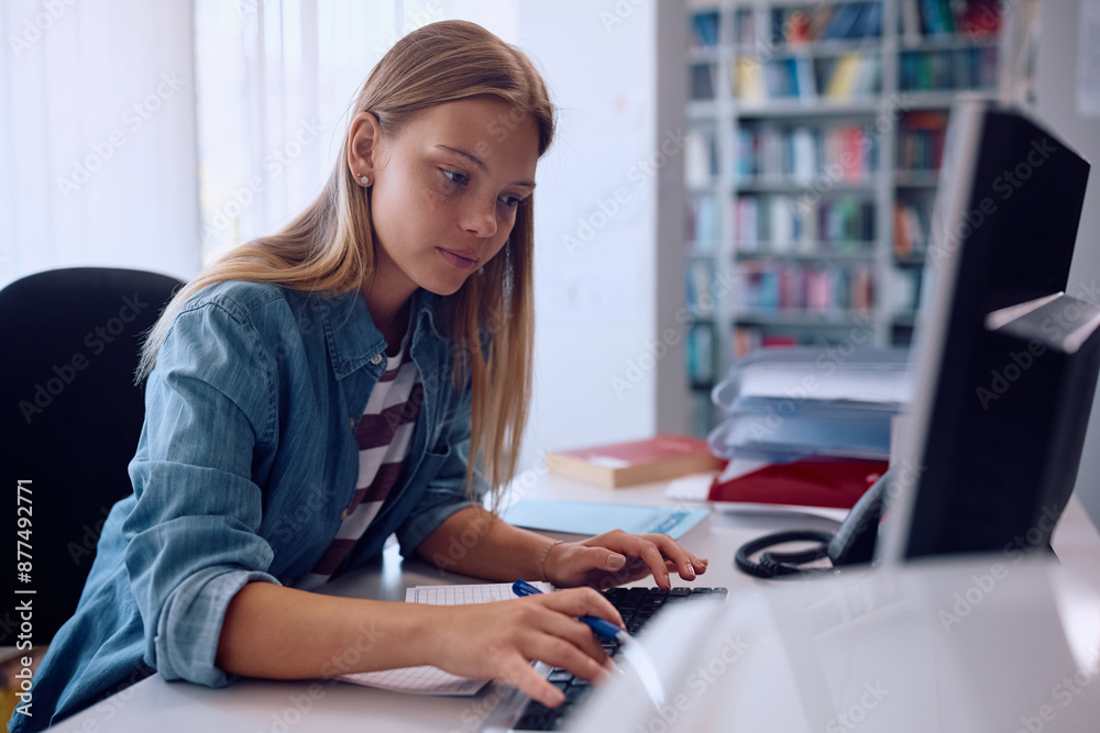 Female student using computer while studying in library. Female student using computer while studying in library.