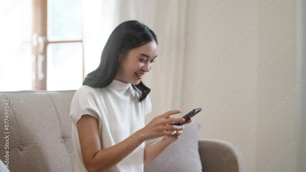 Asian girl looking at mobile phone and smiling, Enjoying on smart phone Asian girl looking at mobile phone and smiling, Enjoying on smart phone