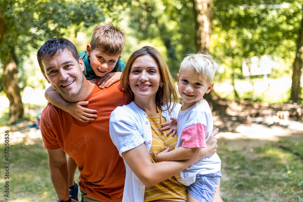 Family of four bonding in the park. Mother and father hugging with their sons. Family of four bonding in the park. Mother and father hugging with their sons.