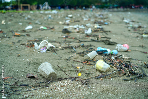 Litter at the sandy beach, Plastic glass left on the beach, waste pollution or garbage on the beach background. Rubbish disposal and trash management, Environmental pollution concept.