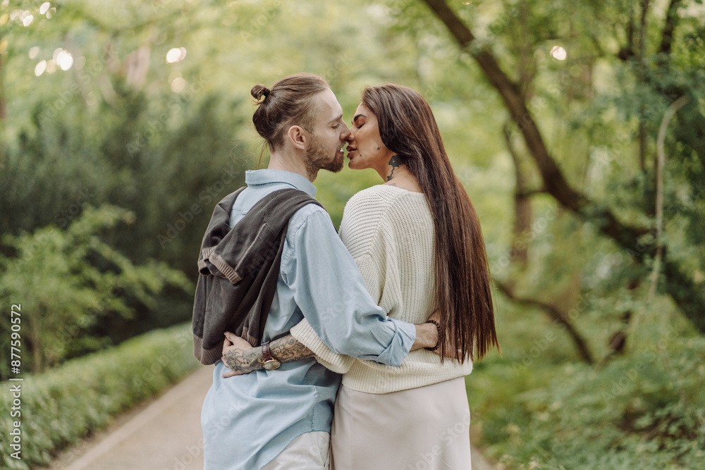 A beautiful couple's engagement portrait by the lovely trees. A stylish young couple, dressed in elegant attire, embraces each other in a lush green field, expressing love and connection. Warsaw. A beautiful couple's engagement portrait by the lovely trees. A stylish young couple, dressed in elegant attire, embraces each other in a lush green field, expressing love and connection. Warsaw.