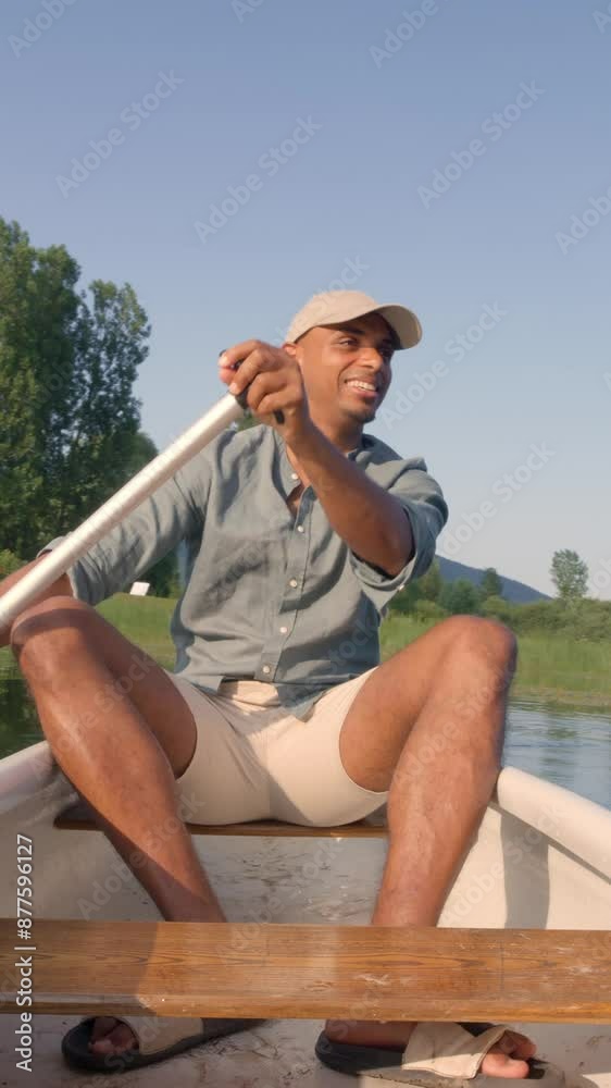 Smiling young man enjoying holiday travel activity on the lake, paddling a canoe and relaxing surrounded by peaceful summer nature, front view. Vertical video Smiling young man enjoying holiday travel activity on the lake, paddling a canoe and relaxing surrounded by peaceful summer nature, front view. Vertical video