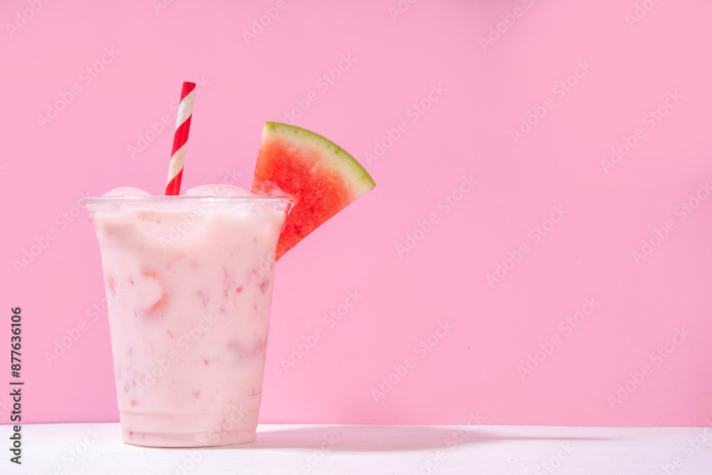 Tasty sweet watermelon milkshake or creamy slushie cocktail, garnished with watermelon slice in plastic cup, copy space Tasty sweet watermelon milkshake or creamy slushie cocktail, garnished with watermelon slice in plastic cup, copy space