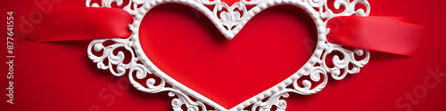 A white ornate heart frame and red ribbon on a red background, perfect for Valentine's Day projects. 
