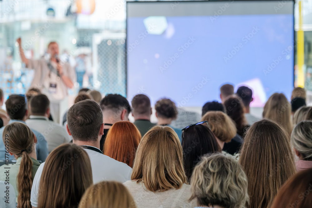 Obraz premium Speaker addresses a diverse audience at a professional conference or seminar, with a focus on engaging the listeners.
