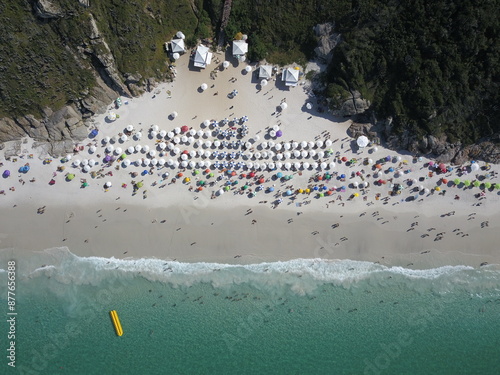 Drone view from the top of a beach in Arraial do Cabo, with tents, people and boats. photo