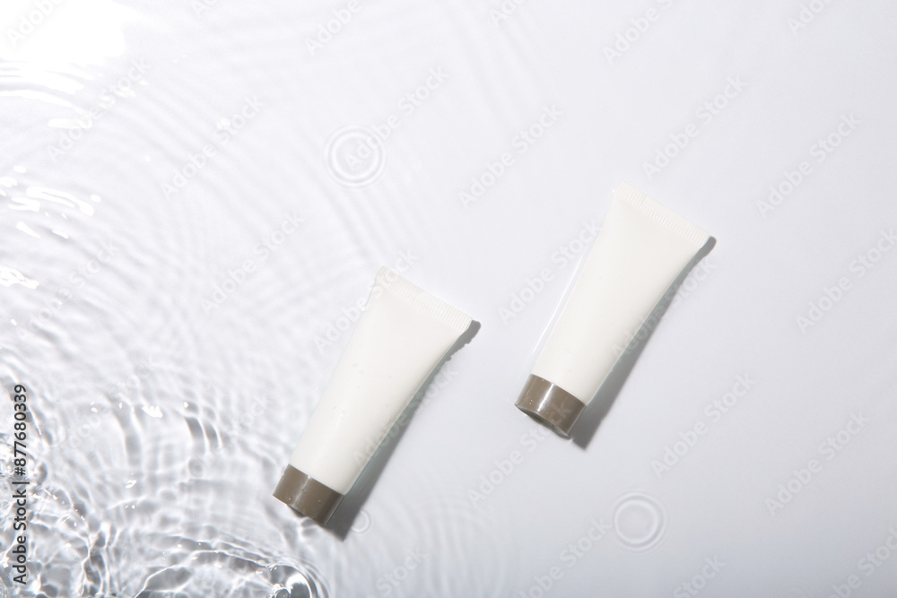 Cosmetic products. Tubes with cream in water on light background, top view Cosmetic products. Tubes with cream in water on light background, top view