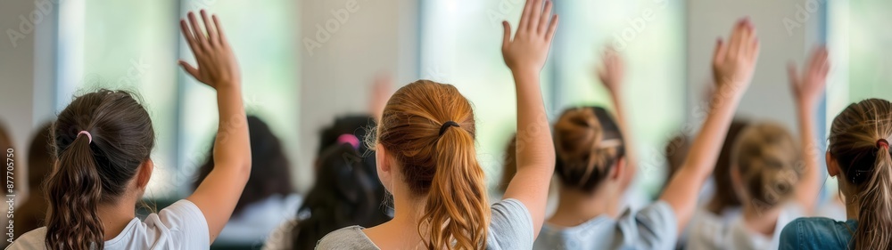 Fototapeta premium group of young girls raising their hands in a classroom