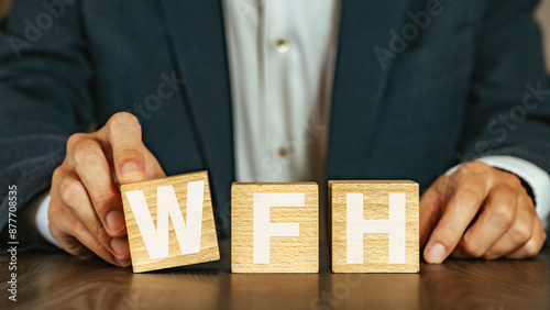 There is wood cube with the word WFH. It is an abbreviation for Work From Home as eye-catching image.