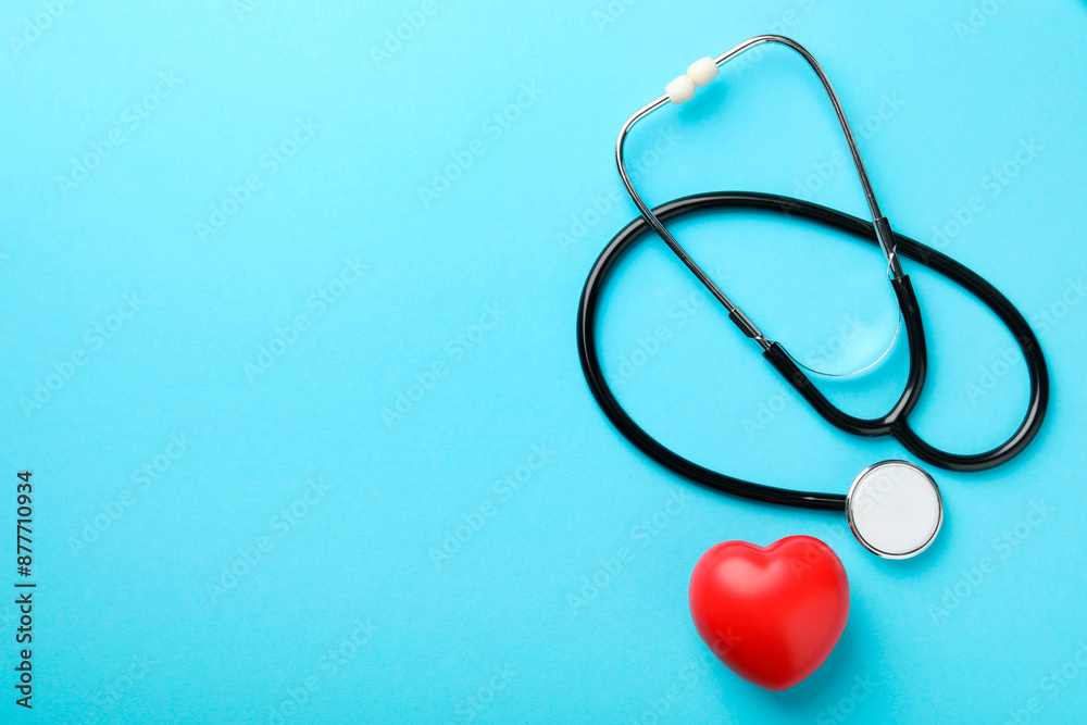 Stethoscope and red heart on light blue background, top view. Space for text Stethoscope and red heart on light blue background, top view. Space for text