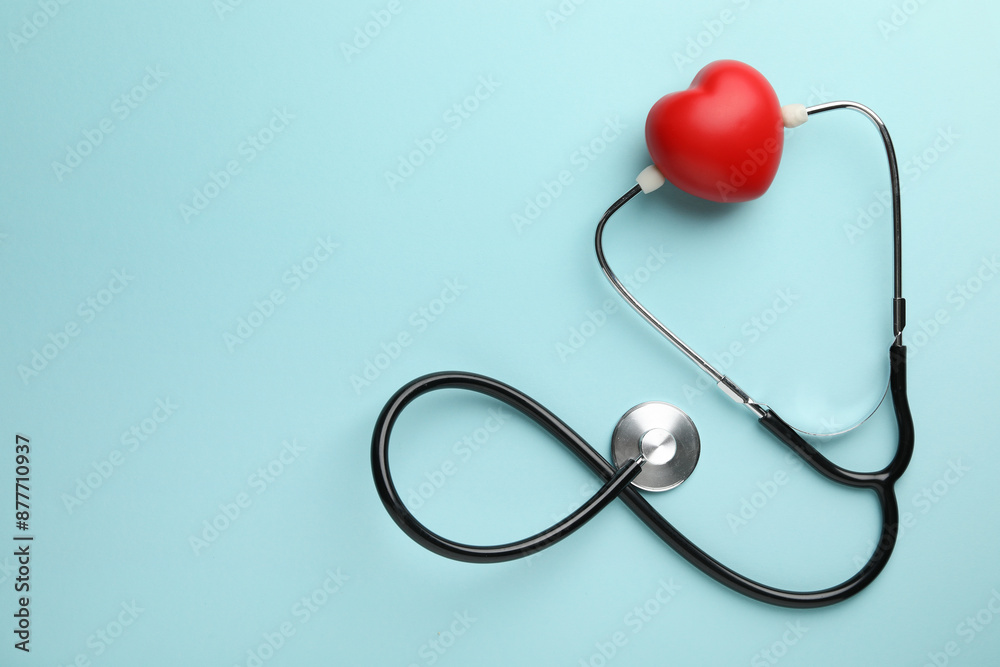 Stethoscope and red heart on light blue background, top view. Space for text Stethoscope and red heart on light blue background, top view. Space for text