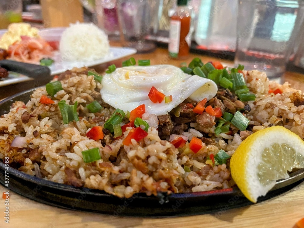 Cast iron plate of fried rice with fried egg on top and side of lemon Cast iron plate of fried rice with fried egg on top and side of lemon