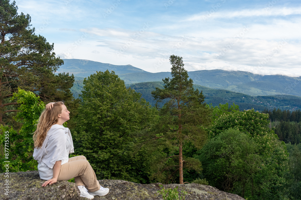 Naklejka premium woman sits on a rock overlooking the mountains. Hiking in the mountains and solo travel. Rest and relaxation. Mocap. High quality photo