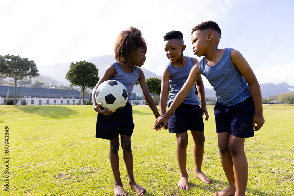 Obraz premium Happy african american schoolchildren playing football on field at school