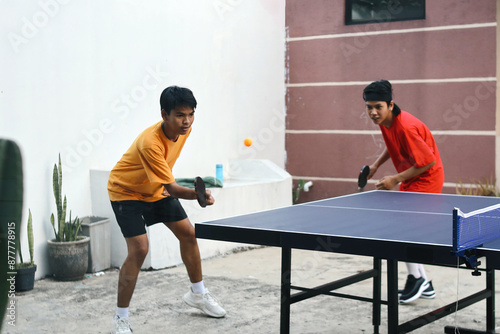 Young Asian Man Sport Team Playing Ping Pong Ball With Forehand Movement photo