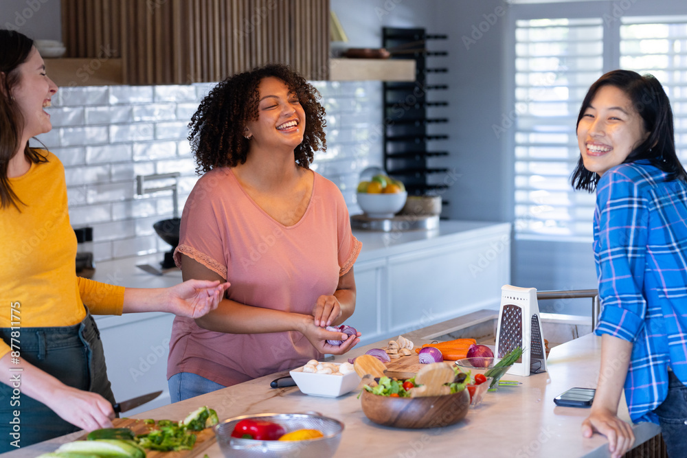 Cooking together, three women friends laughing and preparing food in modern kitchen Cooking together, three women friends laughing and preparing food in modern kitchen