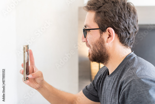 Joven apuesto tomándose una selfie en su habitación con el teléfono móvil 