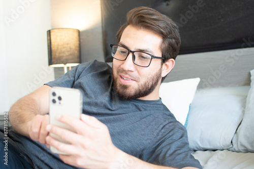 Handsome man using cell phone in room.
