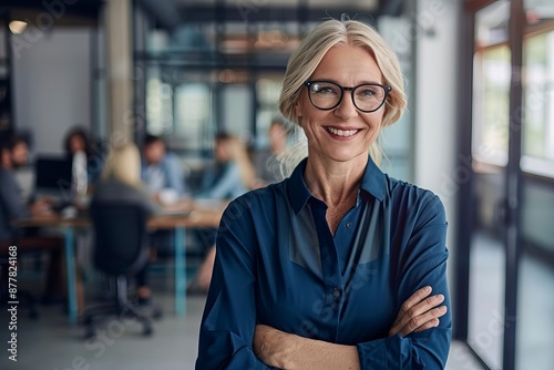 Smiling confident mature business woman leader looking at camera standing in office at team meeting. Male corporate leader ceo executive manager wearing glasses posing  - generative ai © Nia™