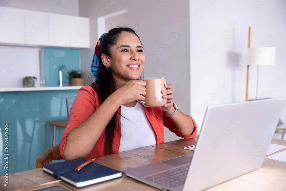 Drinking coffee, woman smiling and working on laptop at home office desk Drinking coffee, woman smiling and working on laptop at home office desk