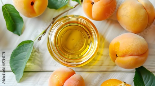 Apricot oil in a glass jar, apricot fruit close-up on a white wooden background, top view. photo