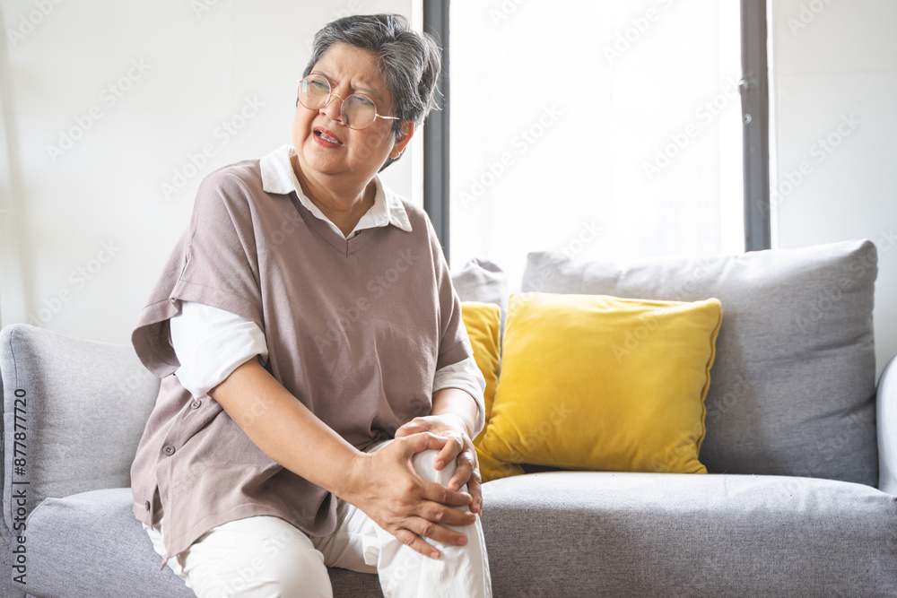 Body arthritis muscles stiff problem, aged woman suffering on leg, pain knee from disease chronic, hand massage rubbing joint injury, mature hurt or sore sitting on sofa at home. Health care people. Body arthritis muscles stiff problem, aged woman suffering on leg, pain knee from disease chronic, hand massage rubbing joint injury, mature hurt or sore sitting on sofa at home. Health care people.