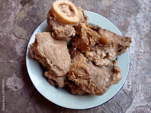 Boiled meat. Beef that has been cooked after being boiled is placed on a plate on the cement floor.  photo