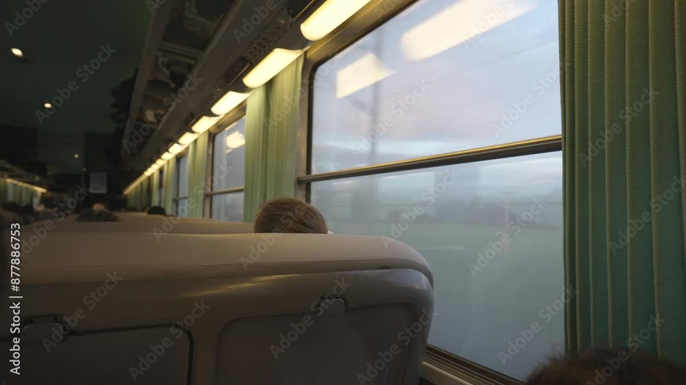 Interior View Of A Train Cabin On A Cloudy Winter Evening Trip, Featuring Green Fields, Large Windows With Warm Lights And Green Curtains, Comfortable Beige Seats, And Seated Passengers Heads Interior View Of A Train Cabin On A Cloudy Winter Evening Trip, Featuring Green Fields, Large Windows With Warm Lights And Green Curtains, Comfortable Beige Seats, And Seated Passengers Heads