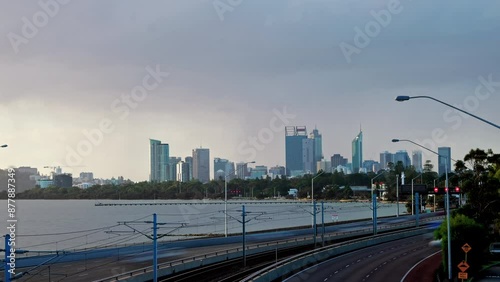 Grey rain clouds sweep over Perth City on bleak stormy day. Swan River with long jetty and freeway in foreground - timelapse