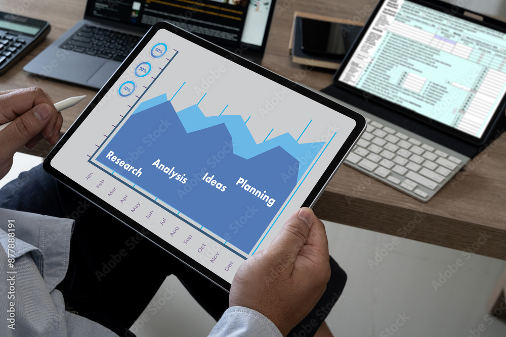 A businessman with a tablet graph in his hand examining In the office, a statistical financial chart report document Technology for business reports A businessman with a tablet graph in his hand examining In the office, a statistical financial chart report document Technology for business reports