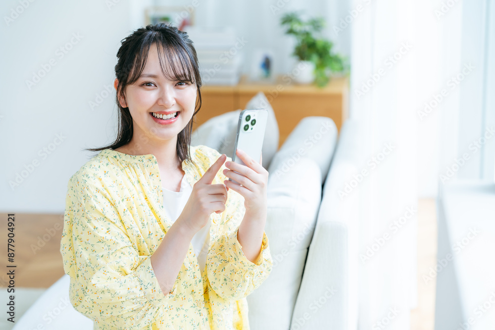 部屋でスマホを操作する若い女性 部屋でスマホを操作する若い女性