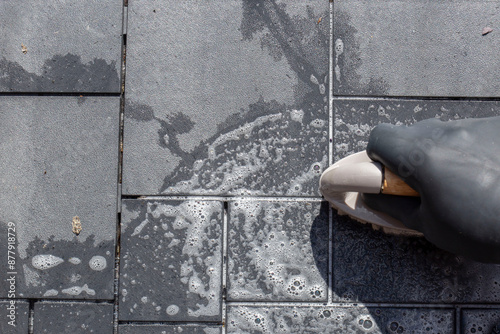 Fotografia Person scrubbing composite decking tile patio with a hand brush