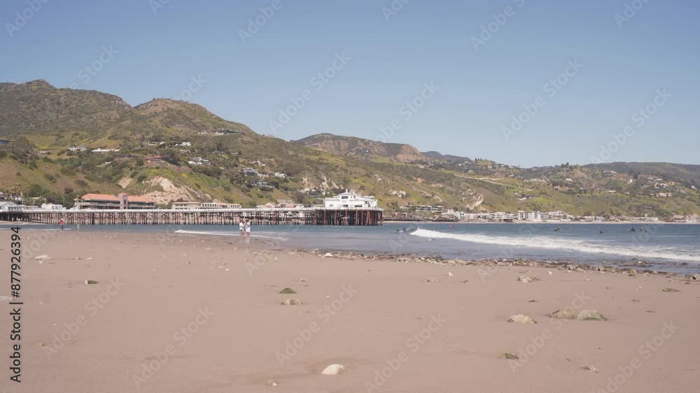 Tourists Enjoying The Sunny Day At The Beach Near Malibu Pier In Southern California, United States. Wide Shot Tourists Enjoying The Sunny Day At The Beach Near Malibu Pier In Southern California, United States. Wide Shot
