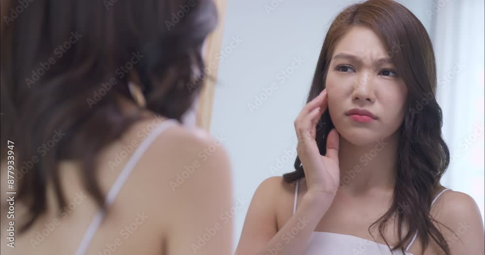 Young woman worried about the wrinkles on her face while looking in the mirror at home. Young woman worried about the wrinkles on her face while looking in the mirror at home.
