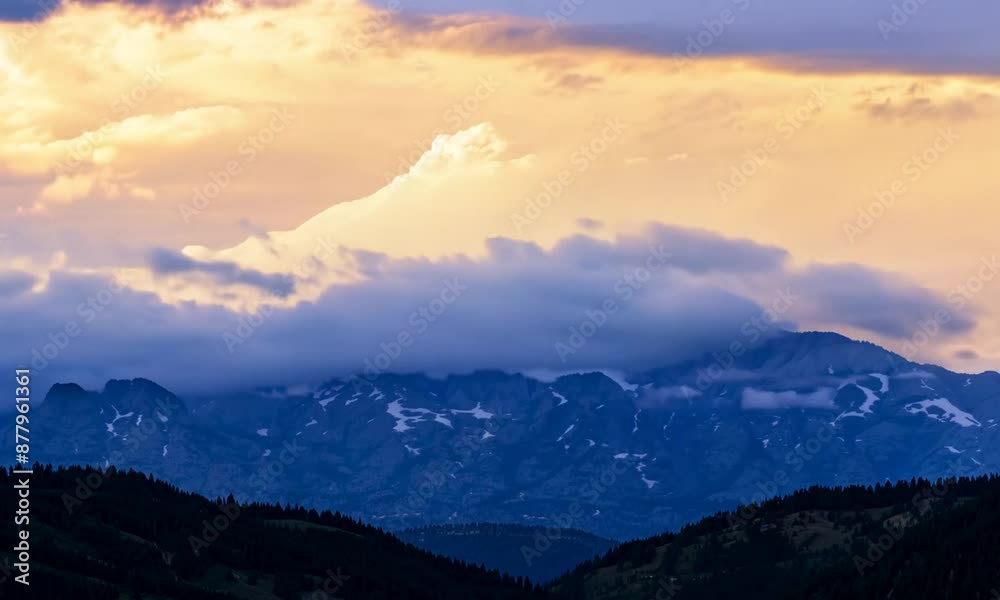 Time-lapse: Clouds rolling over a mountain range. The light changes from dawn to dusk Time-lapse: Clouds rolling over a mountain range. The light changes from dawn to dusk
