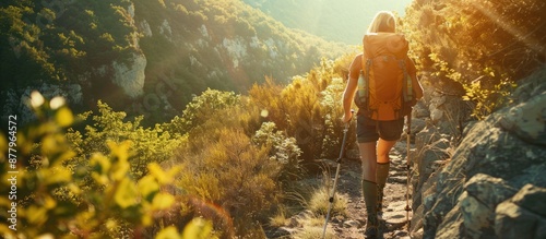 Hiker with backpack walking on a rugged mountain trail at sunrise, surrounded by breathtaking views. AIG62 photo