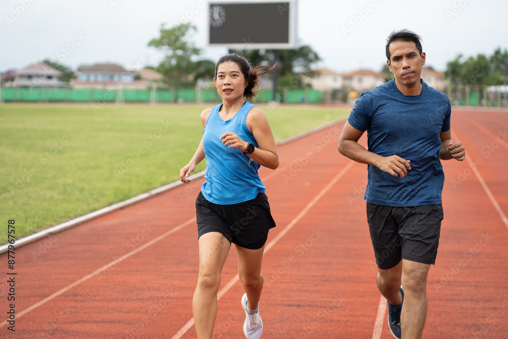 Asia mature woman and man runner training on racetrack and field Asia mature woman and man runner training on racetrack and field