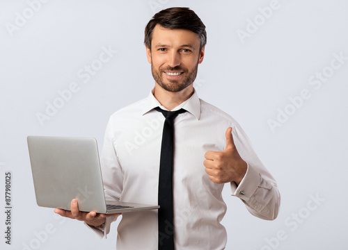 Like. Smiling Man Holding Laptop Gesturing Thumbs-Up Approving Computer Software. White Studio Background