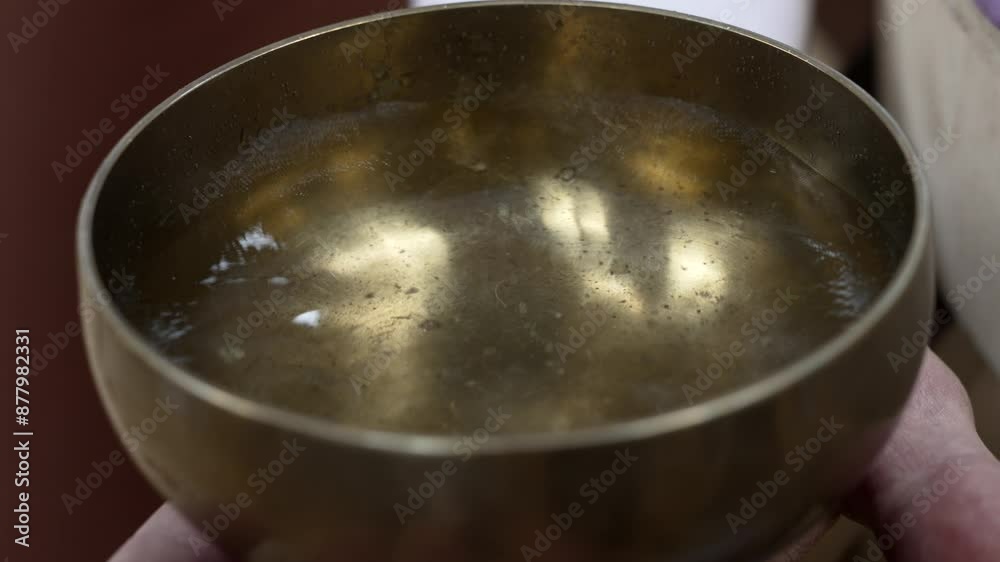 A Hand Rubbing a Partially Filled Singing Bowl With a Wand for a Sound Bath Session in the Sacred Valley of the Cuzco Region, Peru - Close Up A Hand Rubbing a Partially Filled Singing Bowl With a Wand for a Sound Bath Session in the Sacred Valley of the Cuzco Region, Peru - Close Up