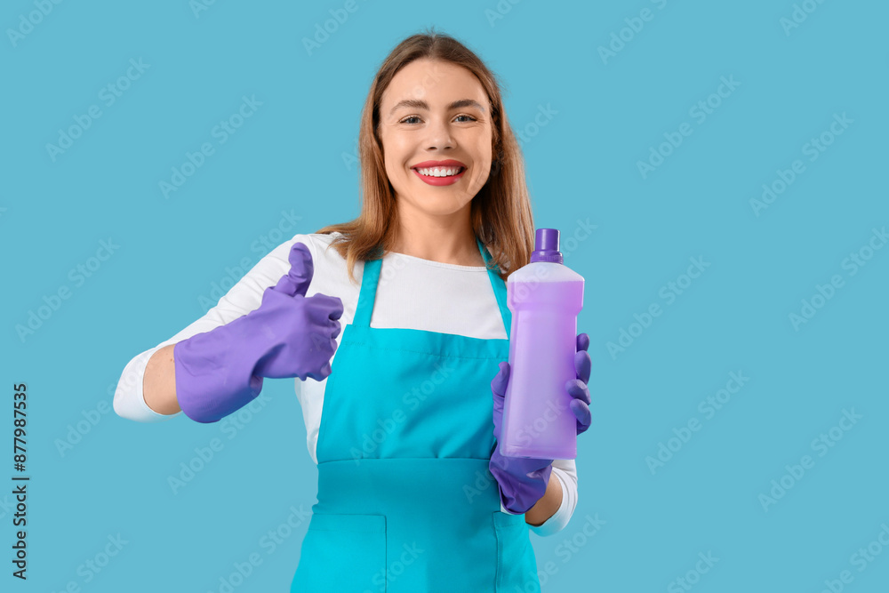 Young woman with bottle of detergent showing thumb-up on blue background Young woman with bottle of detergent showing thumb-up on blue background