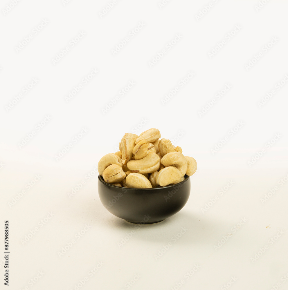 cashew nuts in a woven bamboo container and a black bowl on a plain white background cashew nuts in a woven bamboo container and a black bowl on a plain white background