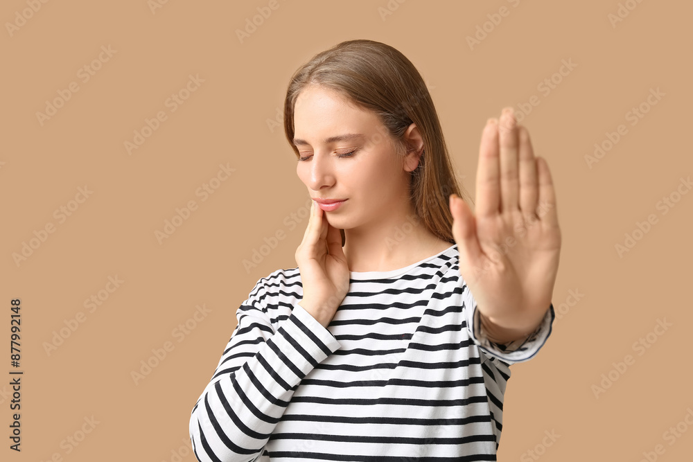 Beautiful young woman suffering from toothache on brown background